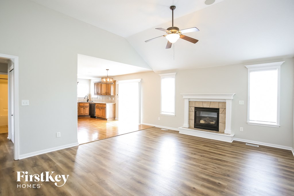 an empty living room with a fireplace and a ceiling fan