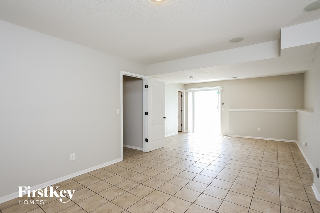 a spacious living room with tile flooring and white walls