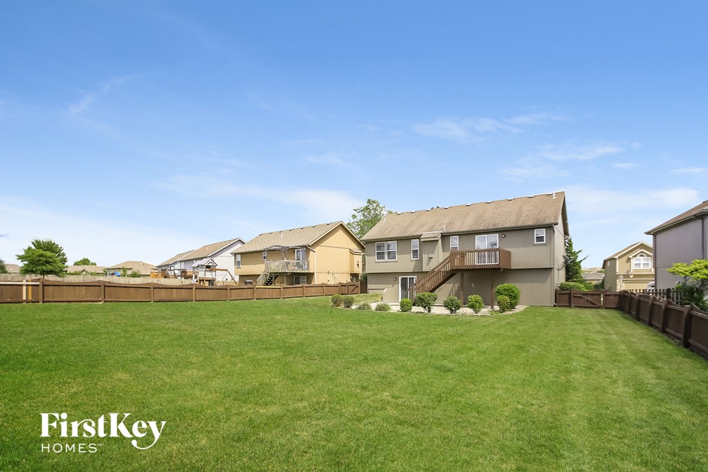 a backyard with a green lawn and a wooden fence