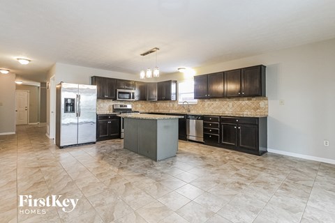 A kitchen with a tile floor and a refrigerator.