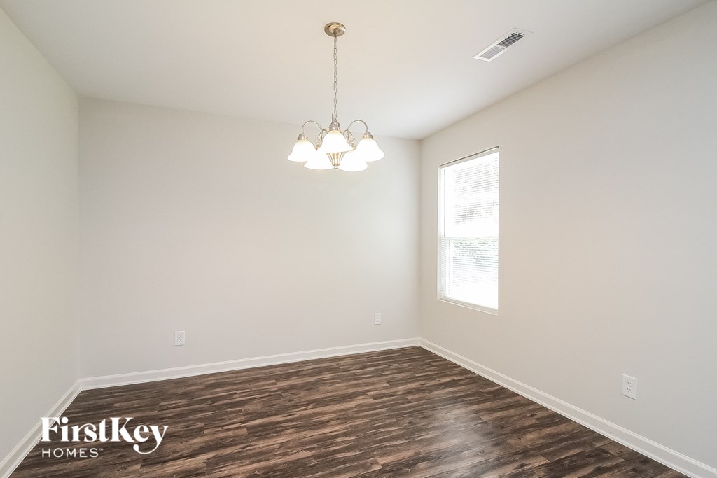 the spacious living room with wood flooring and a chandelier