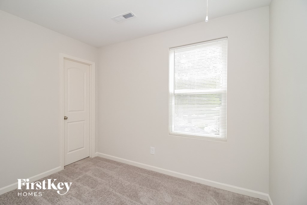 a bedroom with white walls and a white door and a window