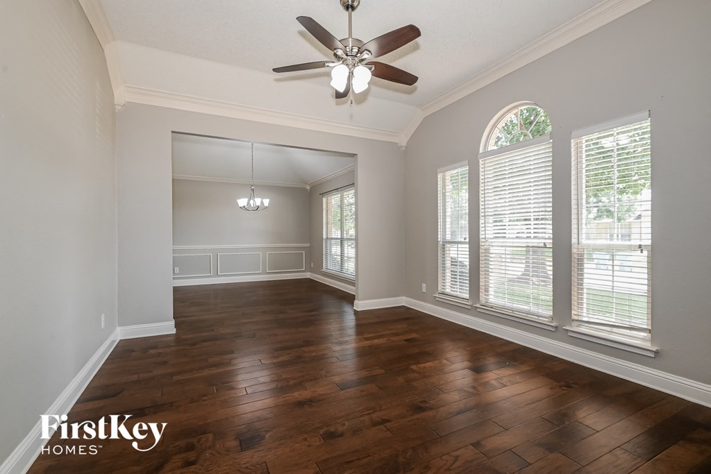 an empty living room with wood floors and a ceiling fan