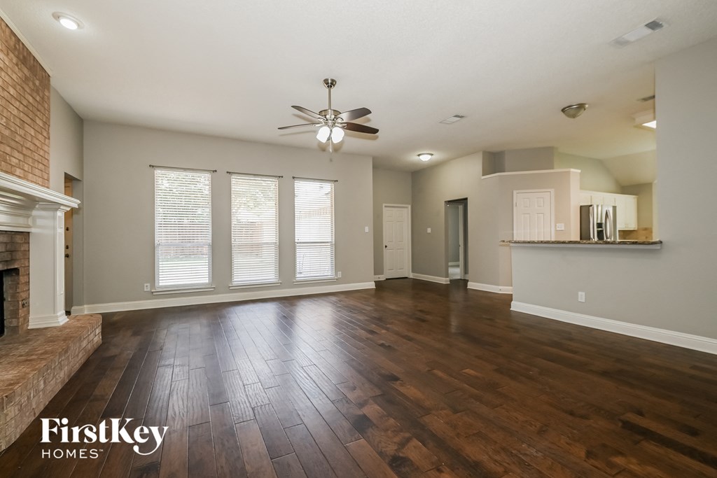 an empty living room with a fireplace and a ceiling fan