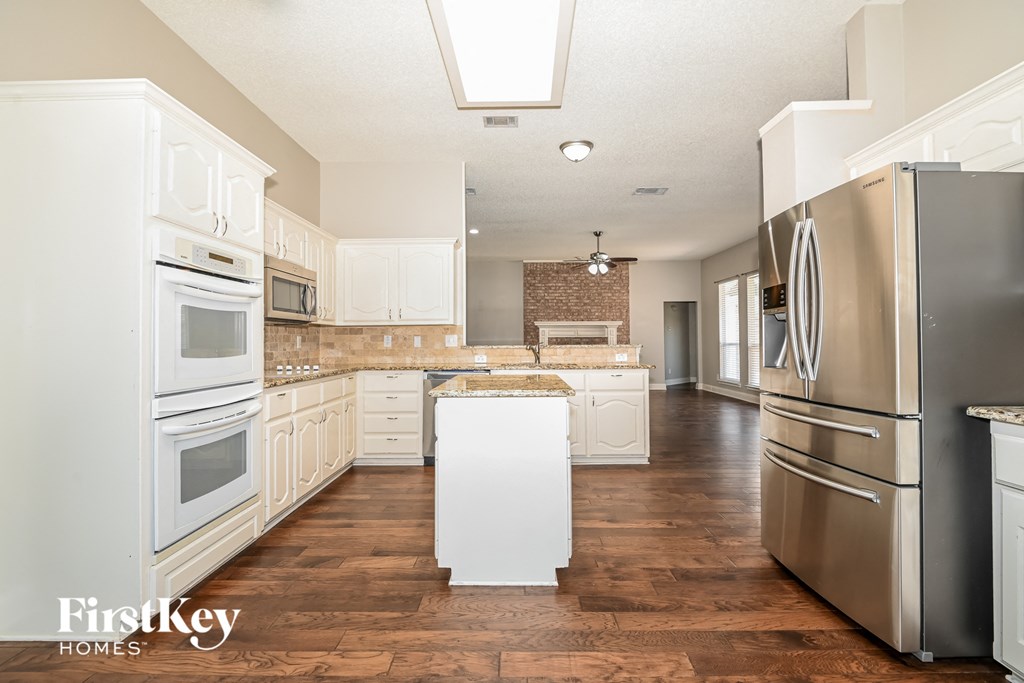 a large kitchen with stainless steel appliances and white cabinets