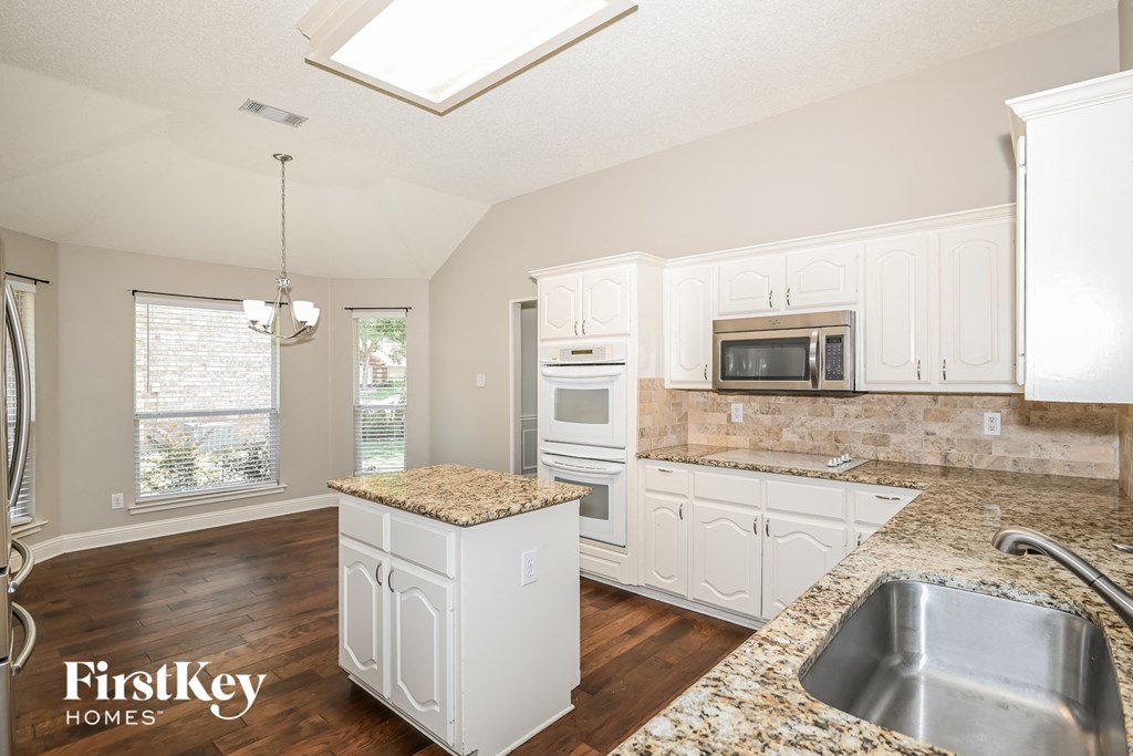 a kitchen with white cabinets and granite counter tops and a sink