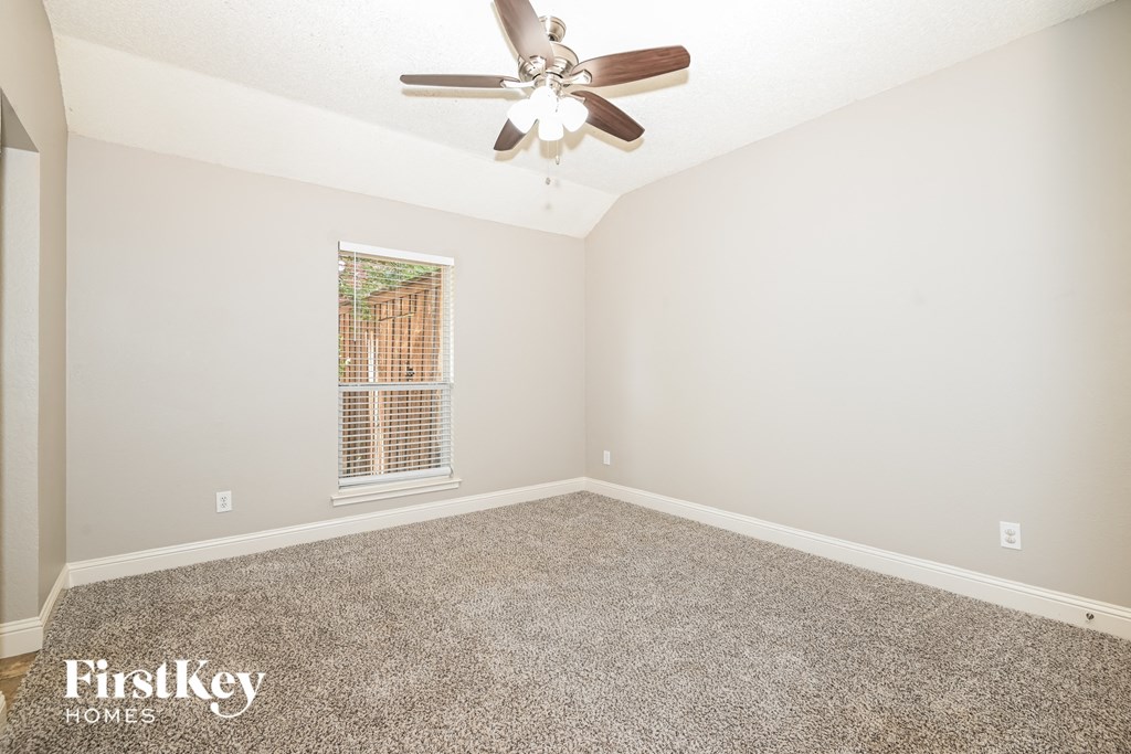 a empty bedroom with a ceiling fan and carpet