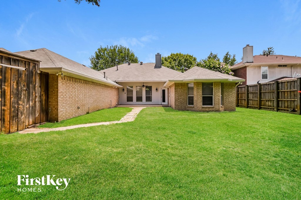 a backyard with a brick house and a fence
