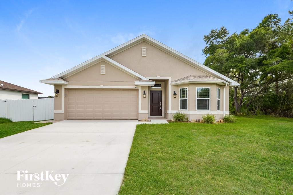 a beige house with a driveway and a lawn