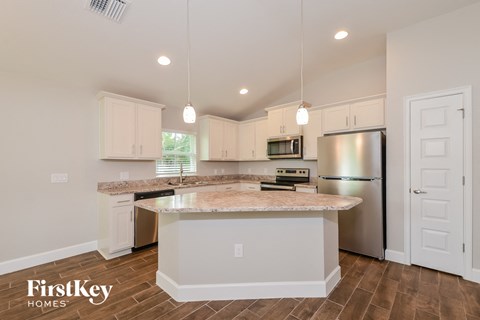 a kitchen with white cabinets and a marble counter top
