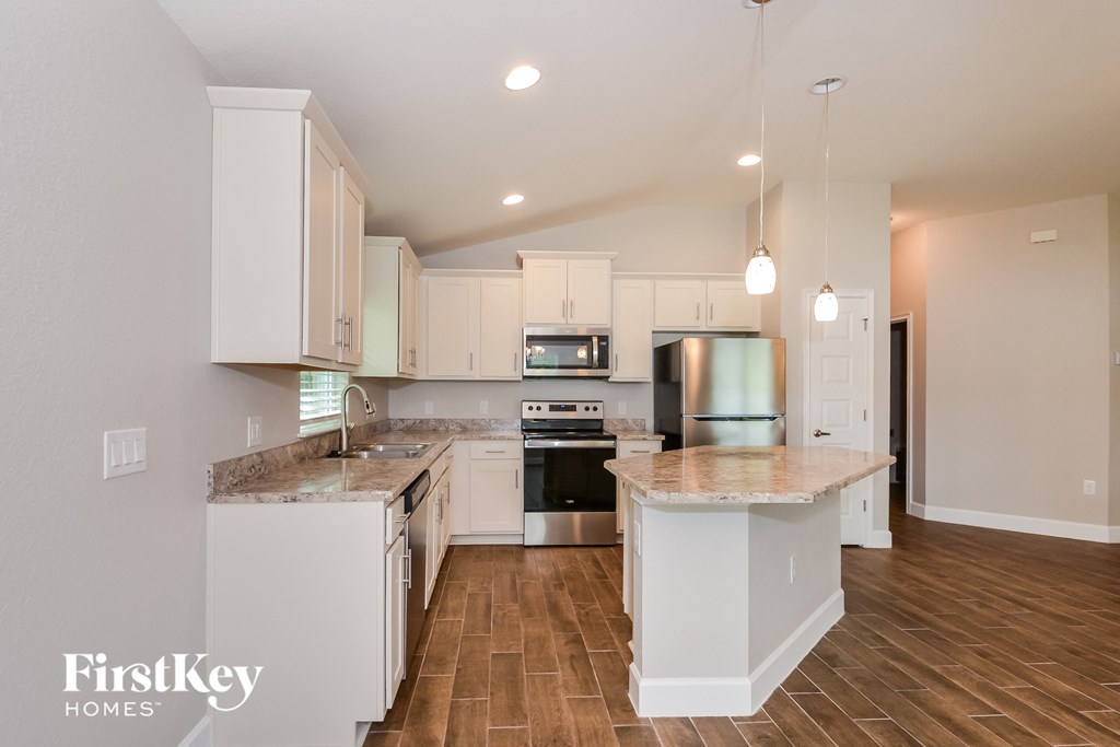 a kitchen with white cabinets and a marble counter top