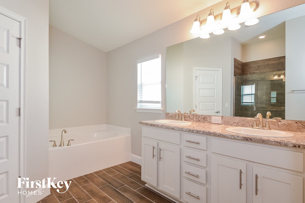a bathroom with two sinks and a tub and a mirror