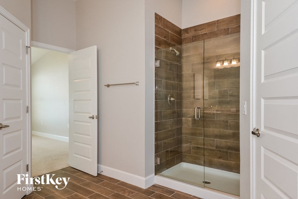 a walk in shower with brown tile and a white door