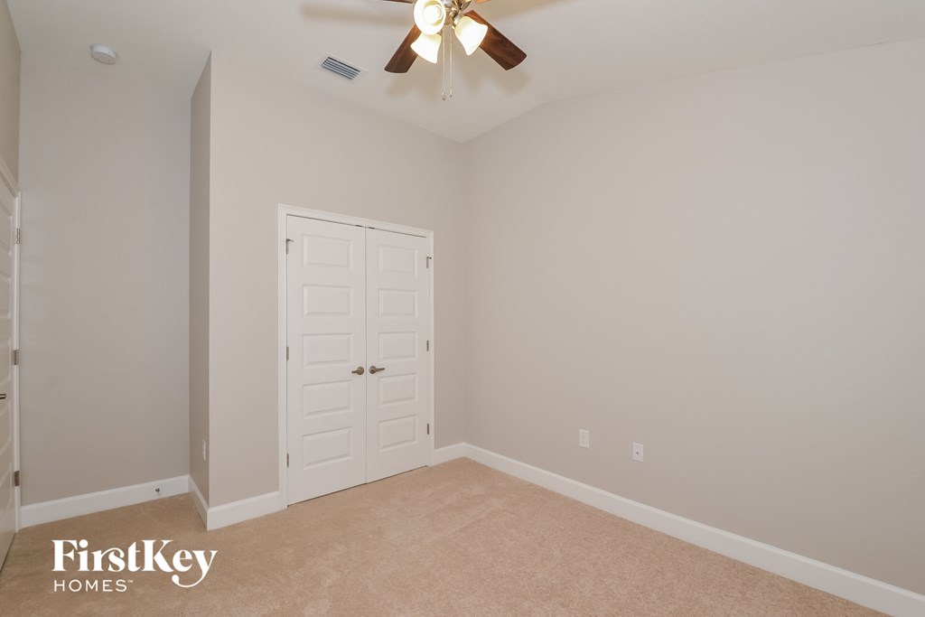 a bedroom with a ceiling fan and a closet