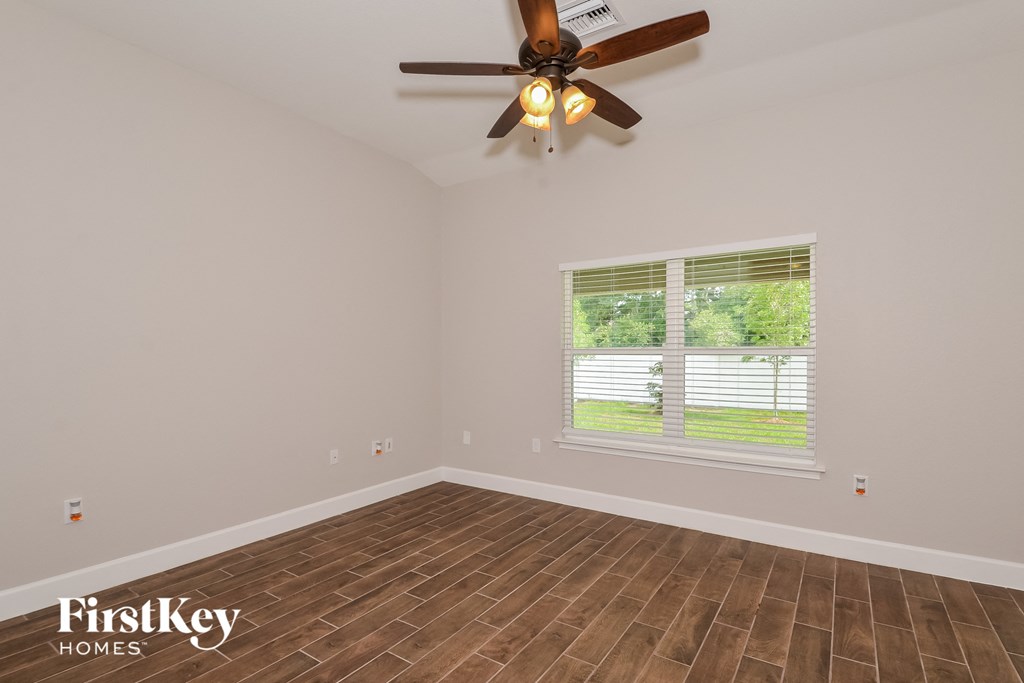 the living room of an empty house with a ceiling fan and a window
