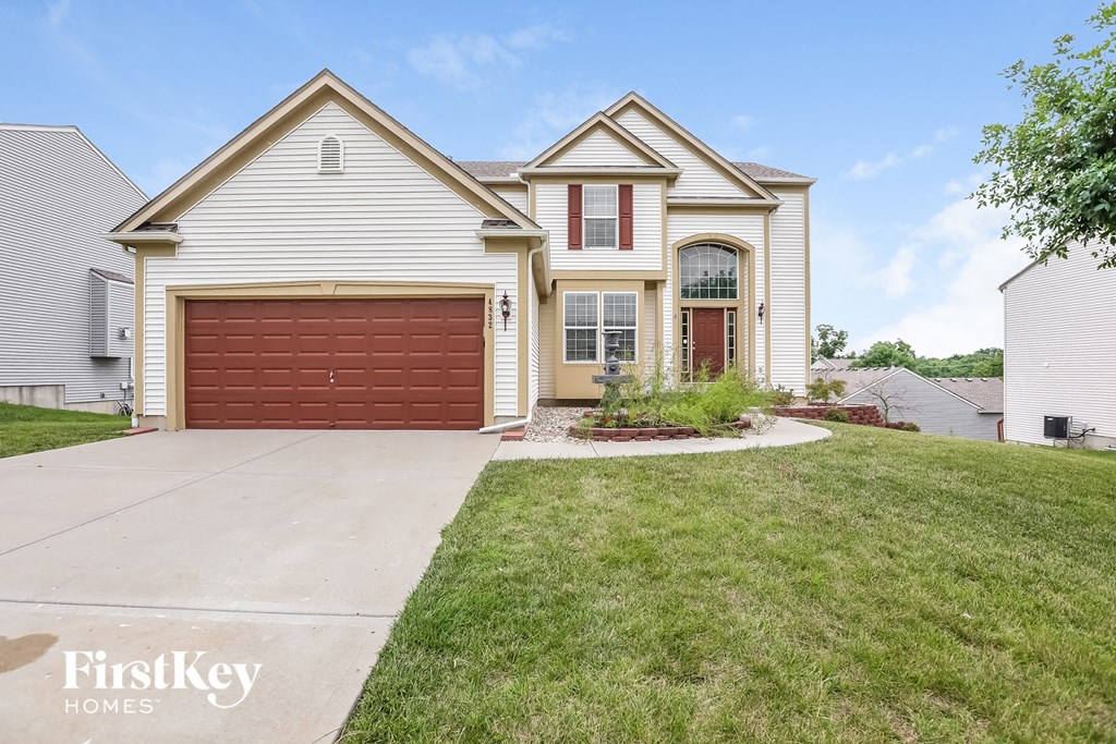 A house with a red garage door is for sale by FirstKey Homes.