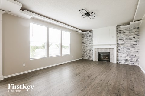 A spacious living room with a stone fireplace and wooden flooring.