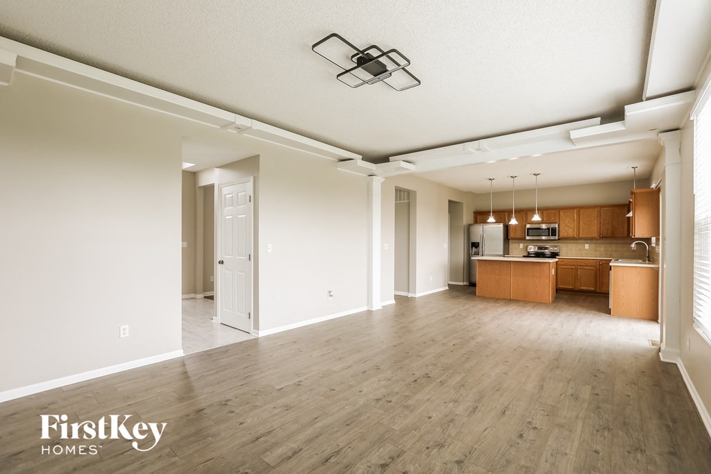A spacious living room with a kitchen in the background.
