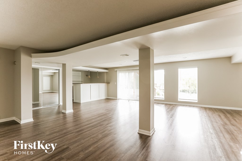 A spacious room with wooden floors and white walls, with a FirstKey Homes logo in the corner.