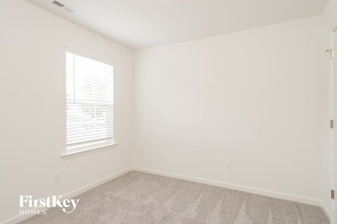 a bedroom with white walls and carpet and a window