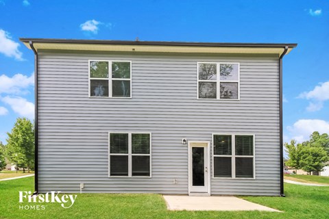 the front of a small house with white siding and green grass