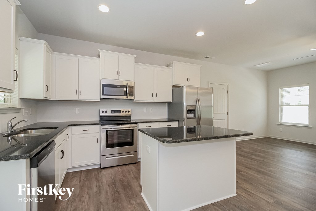 a kitchen with white cabinets and a black counter top