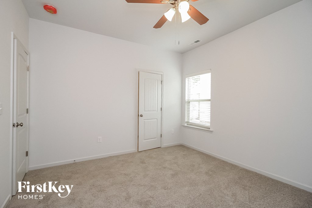 a bedroom with white walls and a white door and a ceiling fan