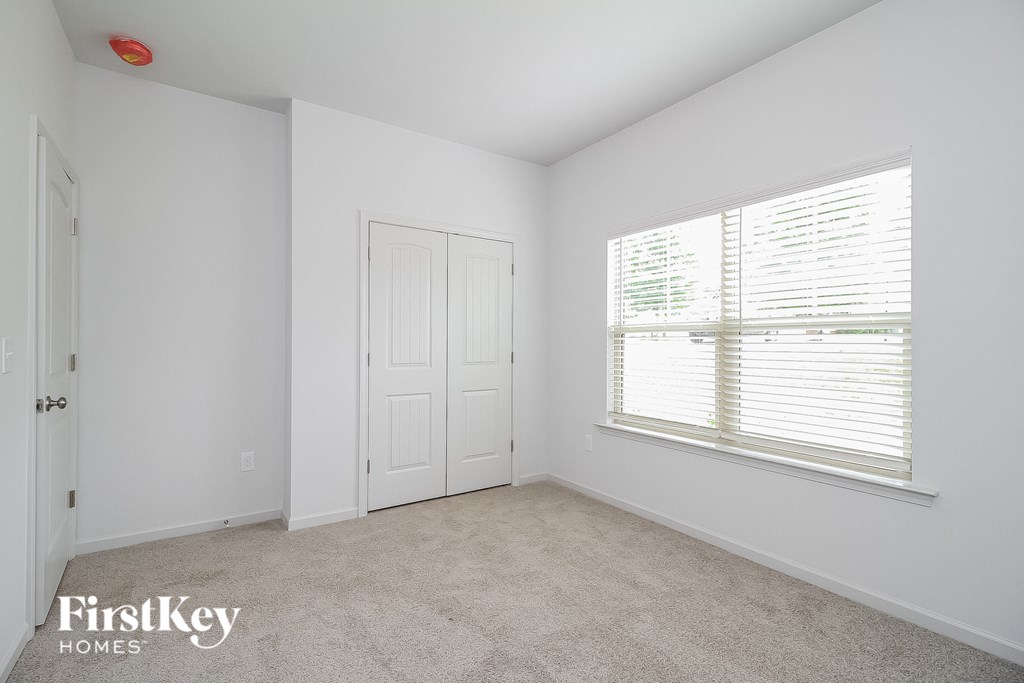 a bedroom with white walls and a large window and a white door