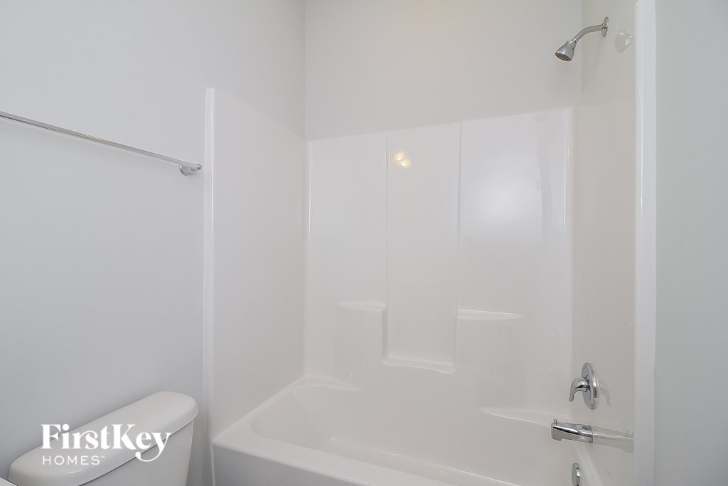 a white bathroom with a white tub and shower and a sink