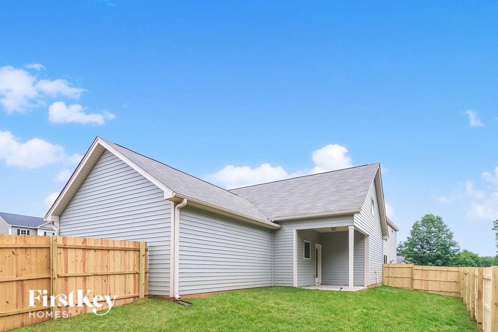 the outside of a house with a yard and a wooden fence