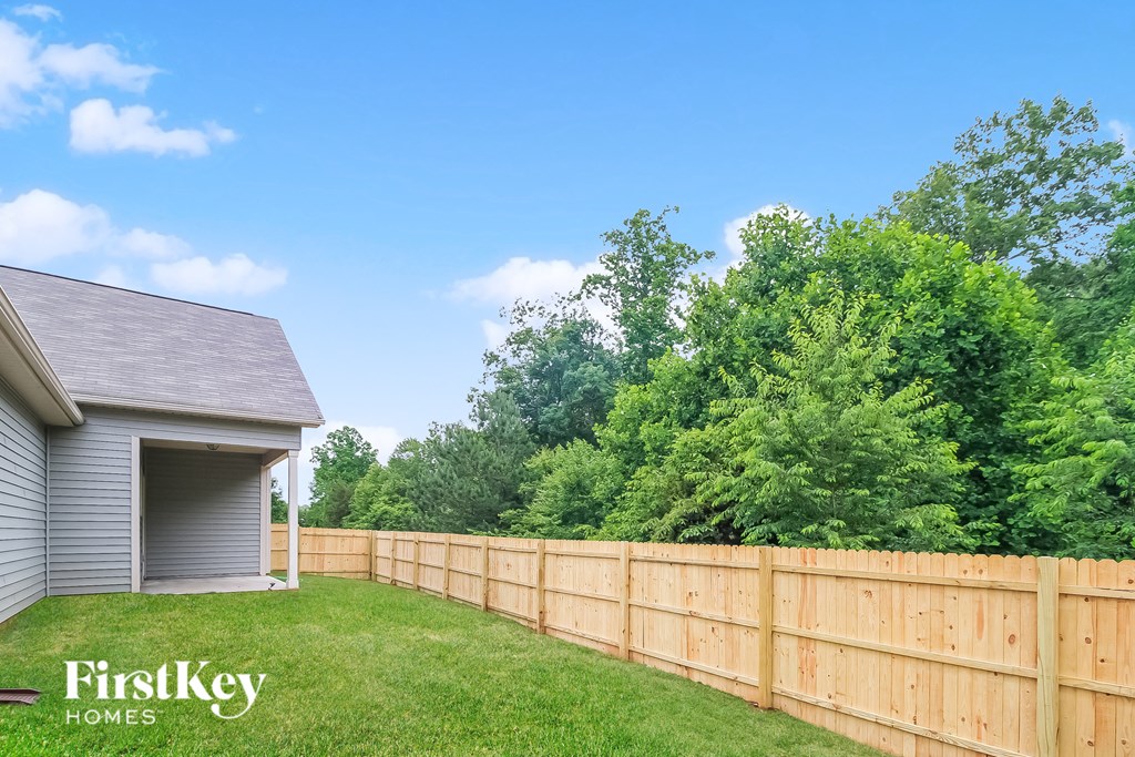 a wooden fence in front of a yard and a house