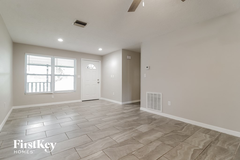 the spacious living room with tile flooring and a white door