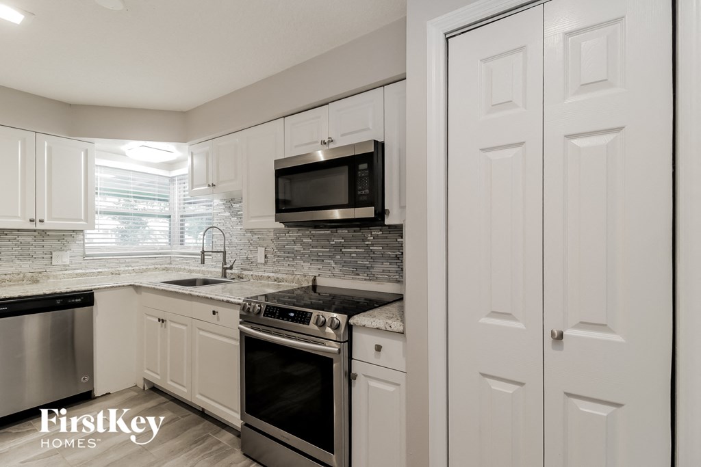 a kitchen with white cabinets and a black stove and a microwave