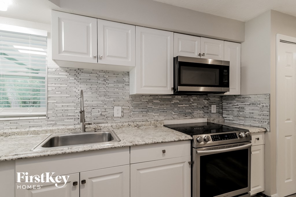 a kitchen with white cabinets and a sink and a microwave