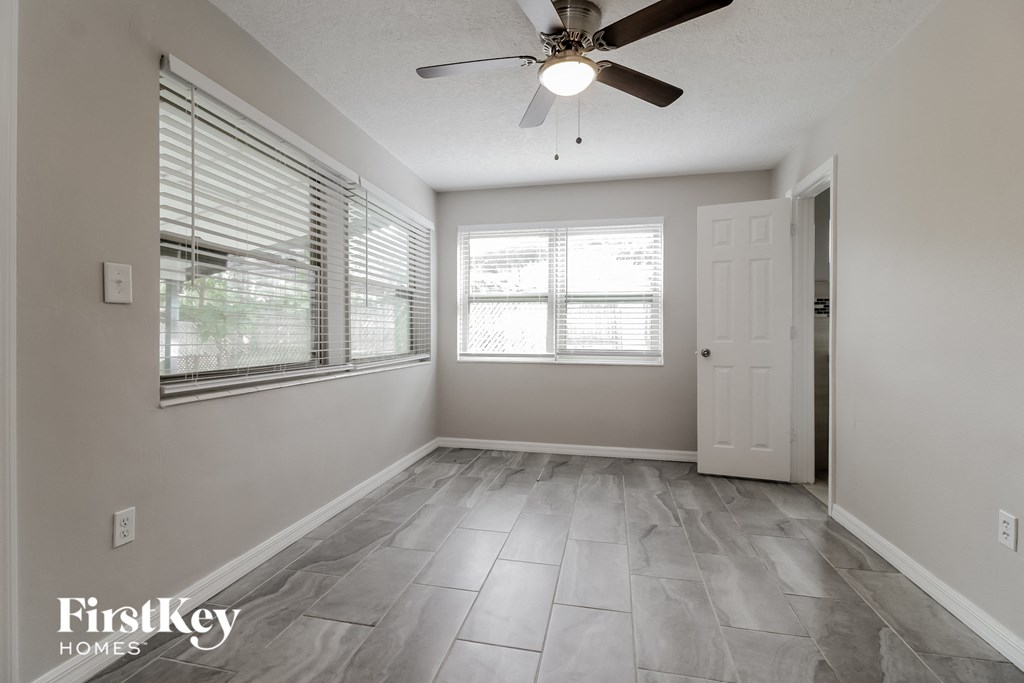 an empty living room with a ceiling fan and two windows