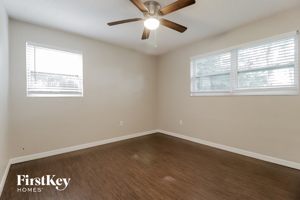 an empty room with a ceiling fan and two windows