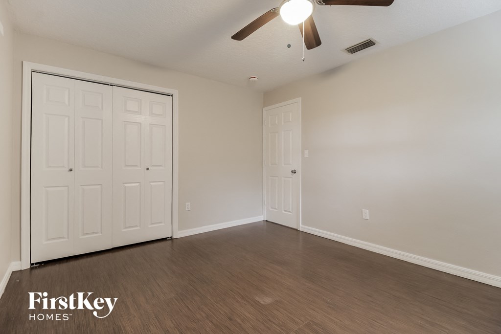 the living room of an empty house with white doors and a ceiling fan