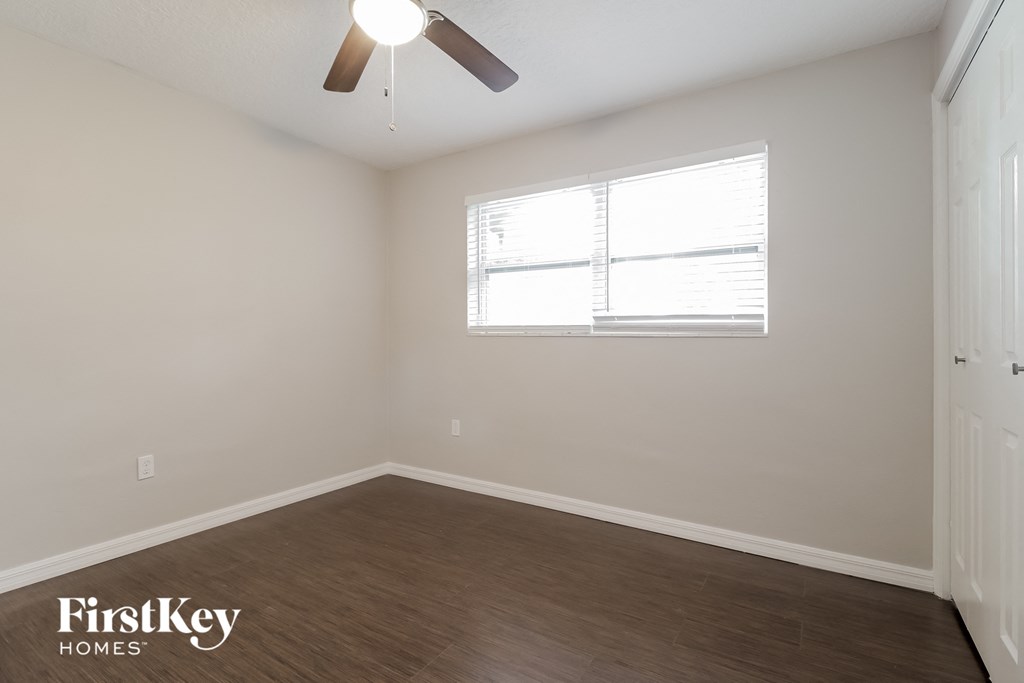 an empty room with a ceiling fan and a window