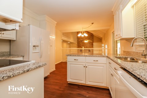 A kitchen with white cabinets and a granite countertop.
