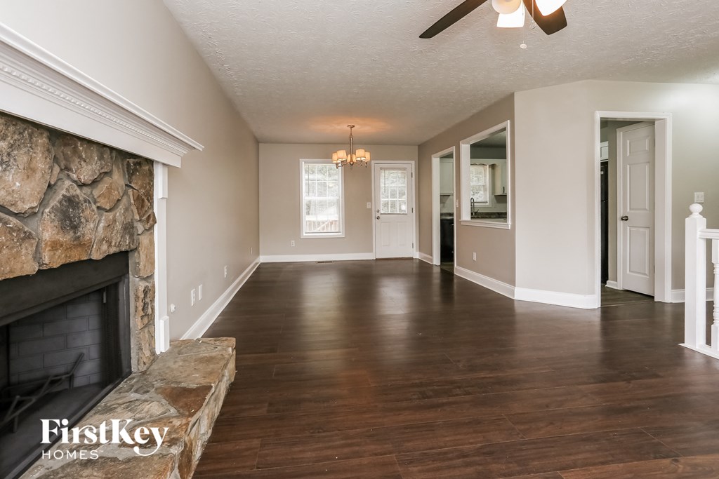 A spacious living room with a stone fireplace and hardwood floors.