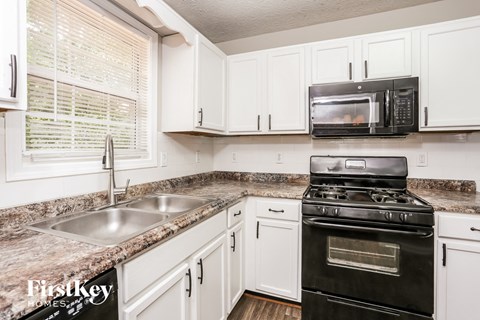 A kitchen with a black stove and white cabinets.