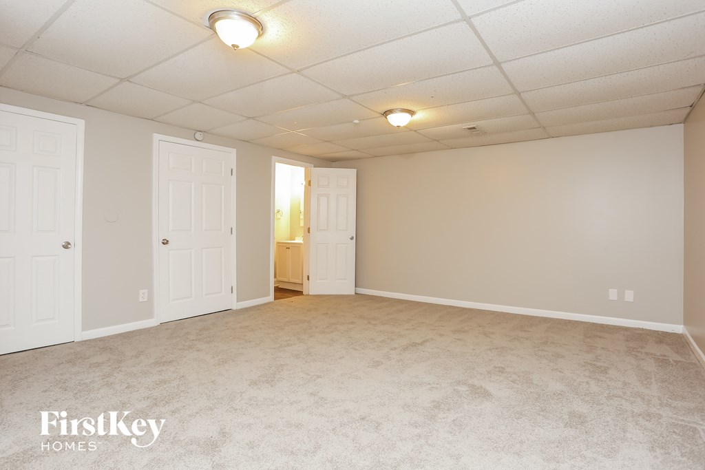 A spacious room with white walls and carpeted floor.