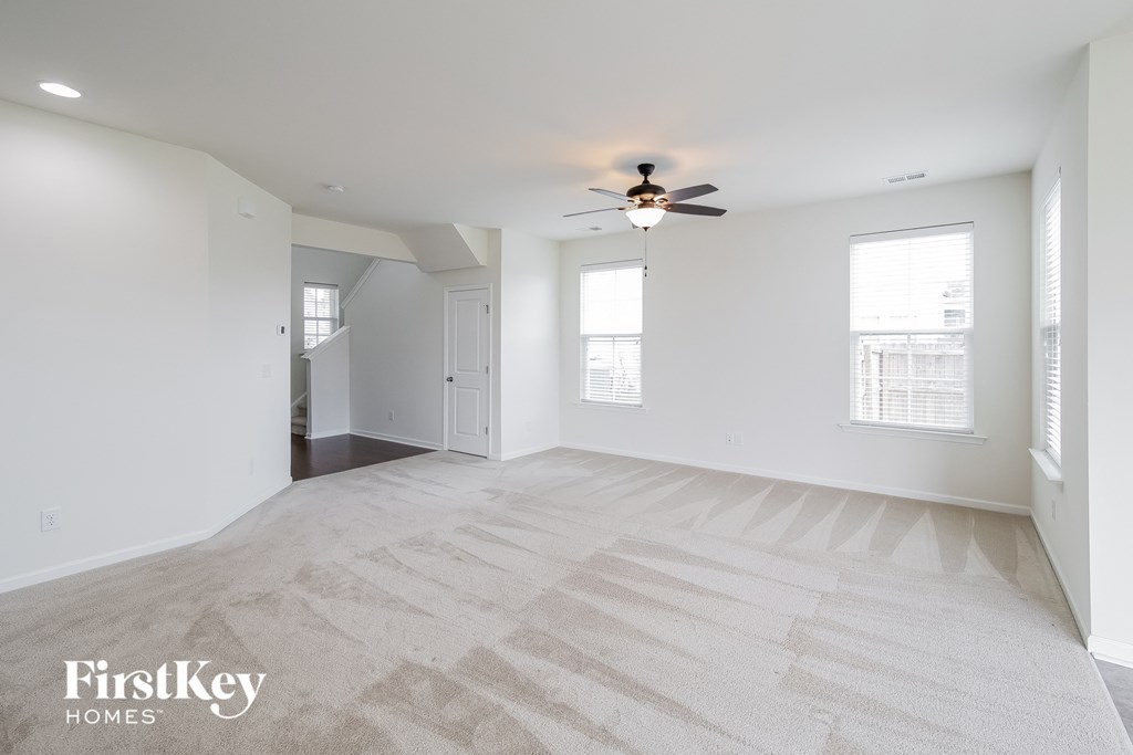 A spacious room with a carpeted floor and a ceiling fan.