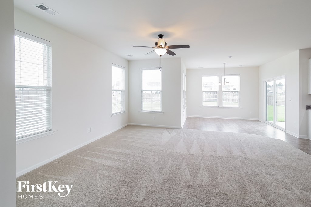 A spacious room with a carpeted floor and a ceiling fan.