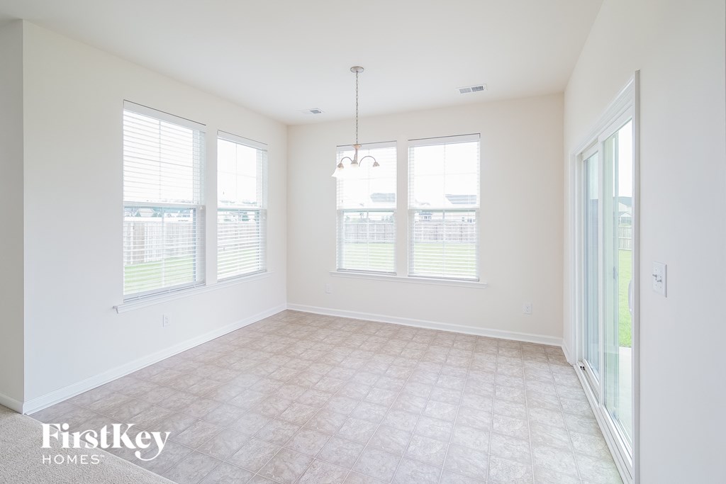 A room with a carpet floor and a chandelier hanging from the ceiling.