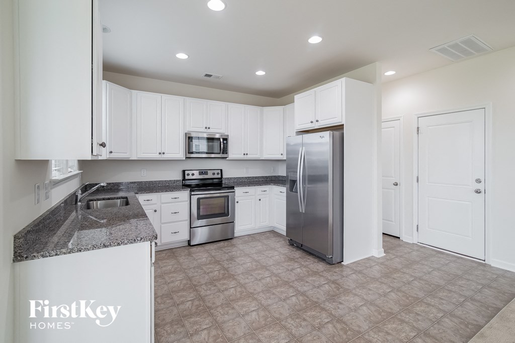 A kitchen with a refrigerator, microwave, oven, and sink.