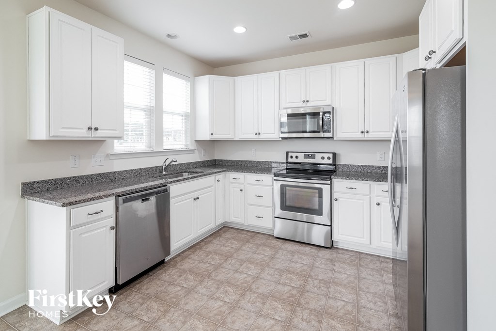 A kitchen with white cabinets and appliances.