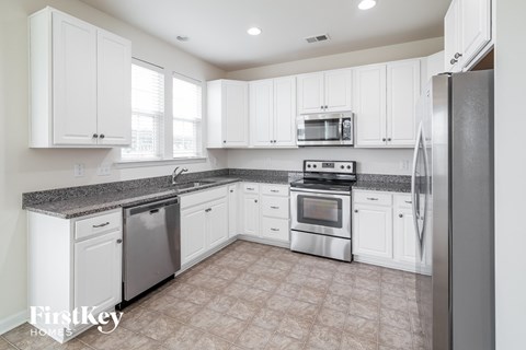 A kitchen with white cabinets and appliances.