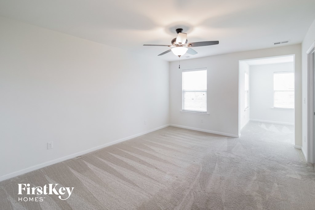 A spacious room with a carpeted floor and a ceiling fan.