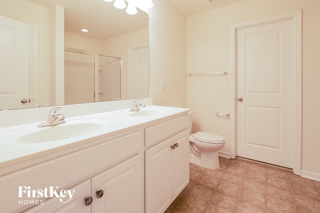 A bathroom with a toilet, sink, and mirror.